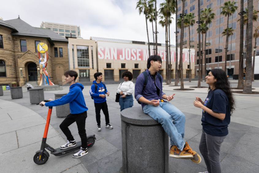SJSU students with a scooter and talking in the Circle of Palms plaza in downtown San José.