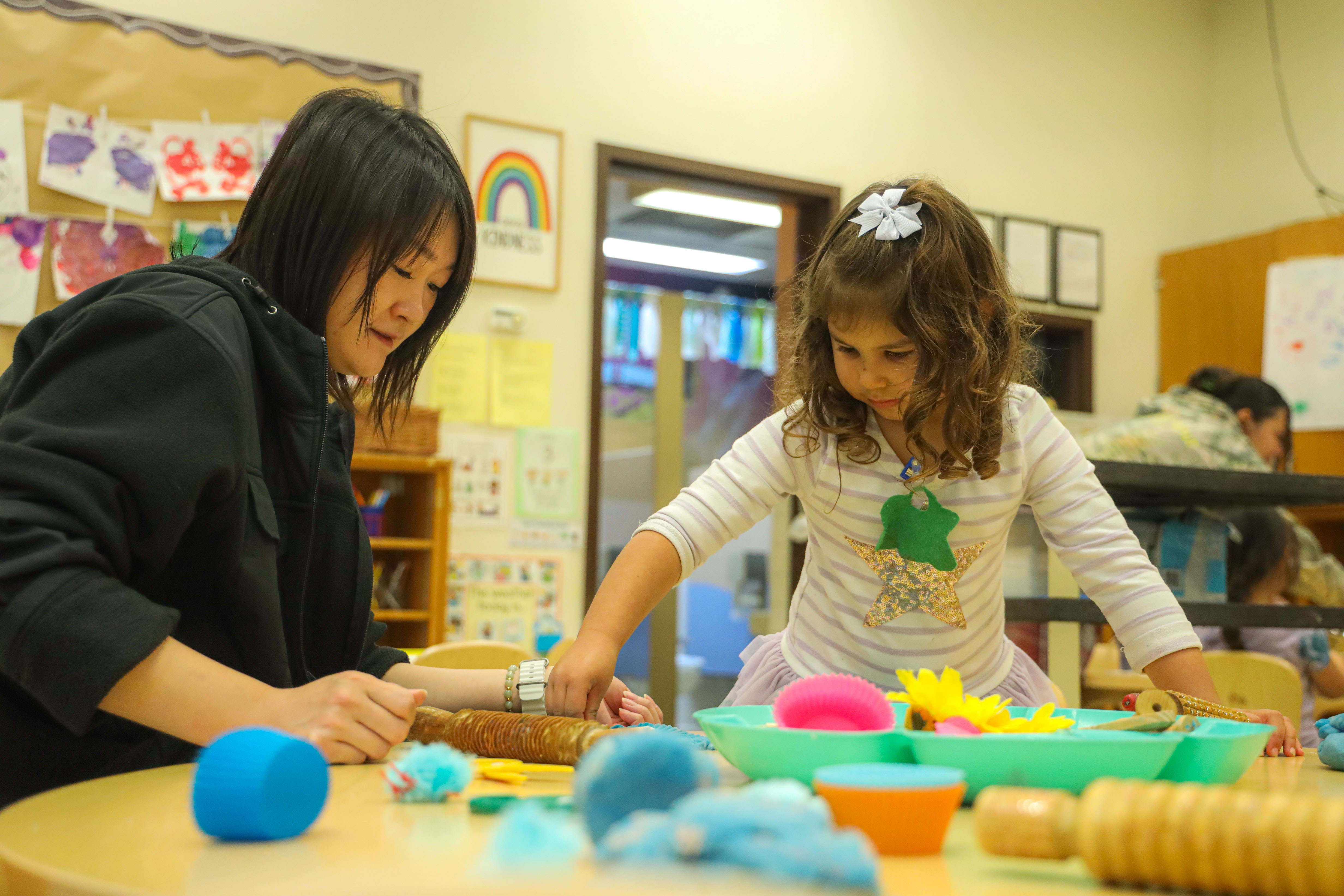 Child playing with claydough with student teacher