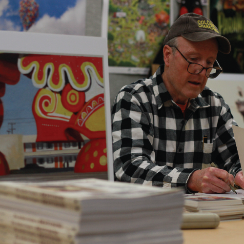 Man at table, signing books