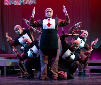 A photo depicting a performance of "Kingdom of Cards," depicting a group of actors dressed as cards posing in striking, rigid poses.