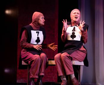 A photo depicting a performance of "Kingdom of Cards," depicting two actresses in playing card uniforms. One is shocked as the other reacts in disgust at what she had said.