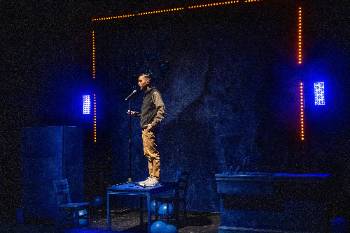 A photo from a performance of "Wolf Play," depicting an actor performing a dialogue in front of a microphone.