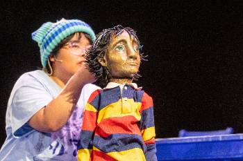 A photo from a performance of "Wolf Play," depicting a close-up of the child doll puppeteered by one of the actors.
