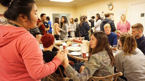 Students engaging socially with each other, gathered at tables or standing in small groups