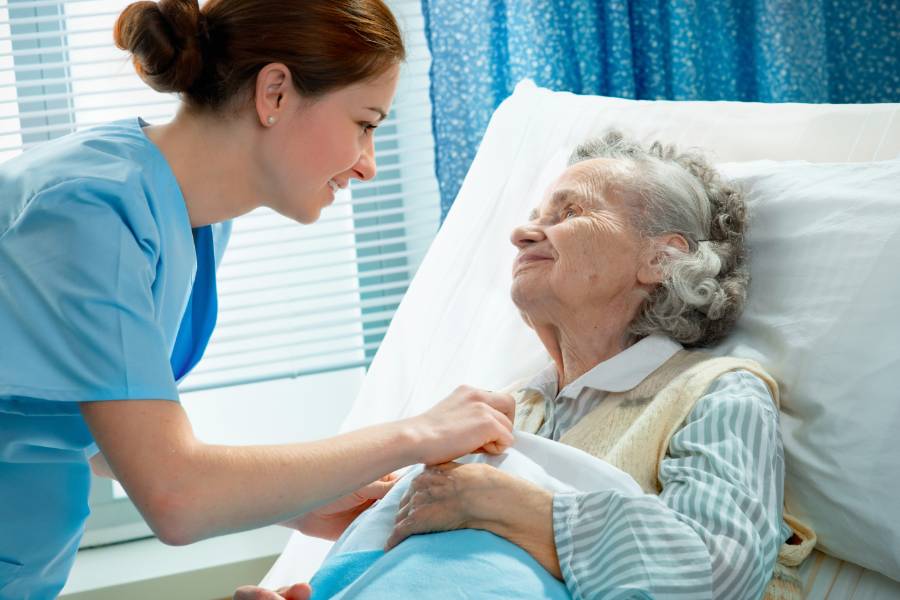 A nurse bedside with an elderly patient.