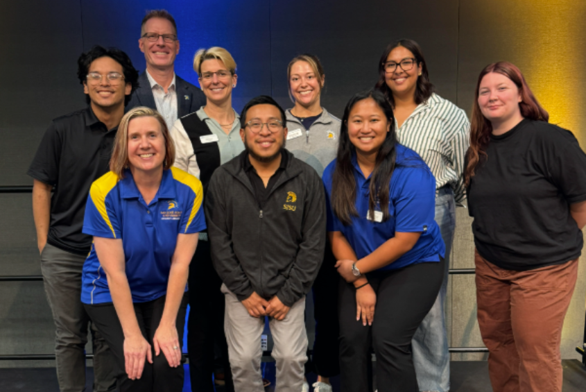 Group photo featuring: Brendan Lorenzana, Coordinator of Campus Programming; Chris Jensen, Ph.D., Director; Amy Prause, Associate Director; Stephanie Rudd, Assistant Director for Recognized Student Organizations; Ana Carrillo, Student Engagement Coordinator - Fraternity & Sorority Life; Trinity Davis, Leadership Development Coordinator. Heather French, Ed.D., AVP and Dean of Students; Jose Garcia, Assistant Director of Fraternity & Sorority Life; Kaytlin Abad, Assistant Director, Campus Programming and Leadership Development.